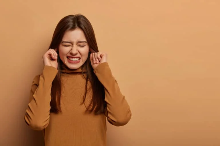 אישה מתוסכלת במצוקה אוטמת אוזניים חומצת שיניים שומעת רעש מטריד נמנעת קול לא נעים לובשת בגדים חומים לא שומעת יותר